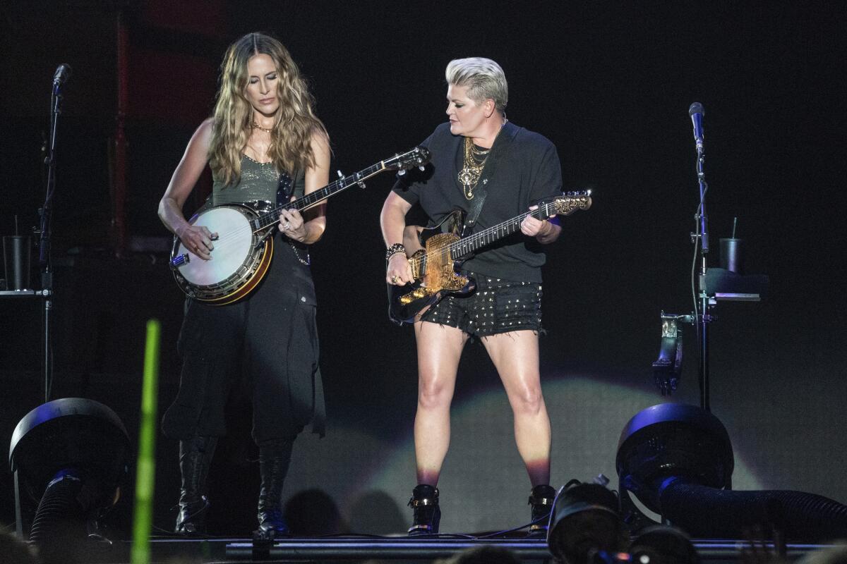 A woman playing a banjo and another woman playing electric guitar on a stage