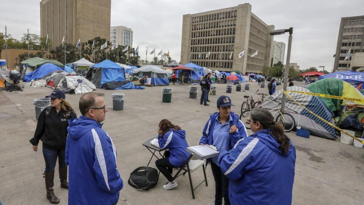 Social workers from the Orange County Social Services Agency visit homeless people living in tents Tuesday at the Plaza of the Flags in Santa Ana to try to connect them with services.