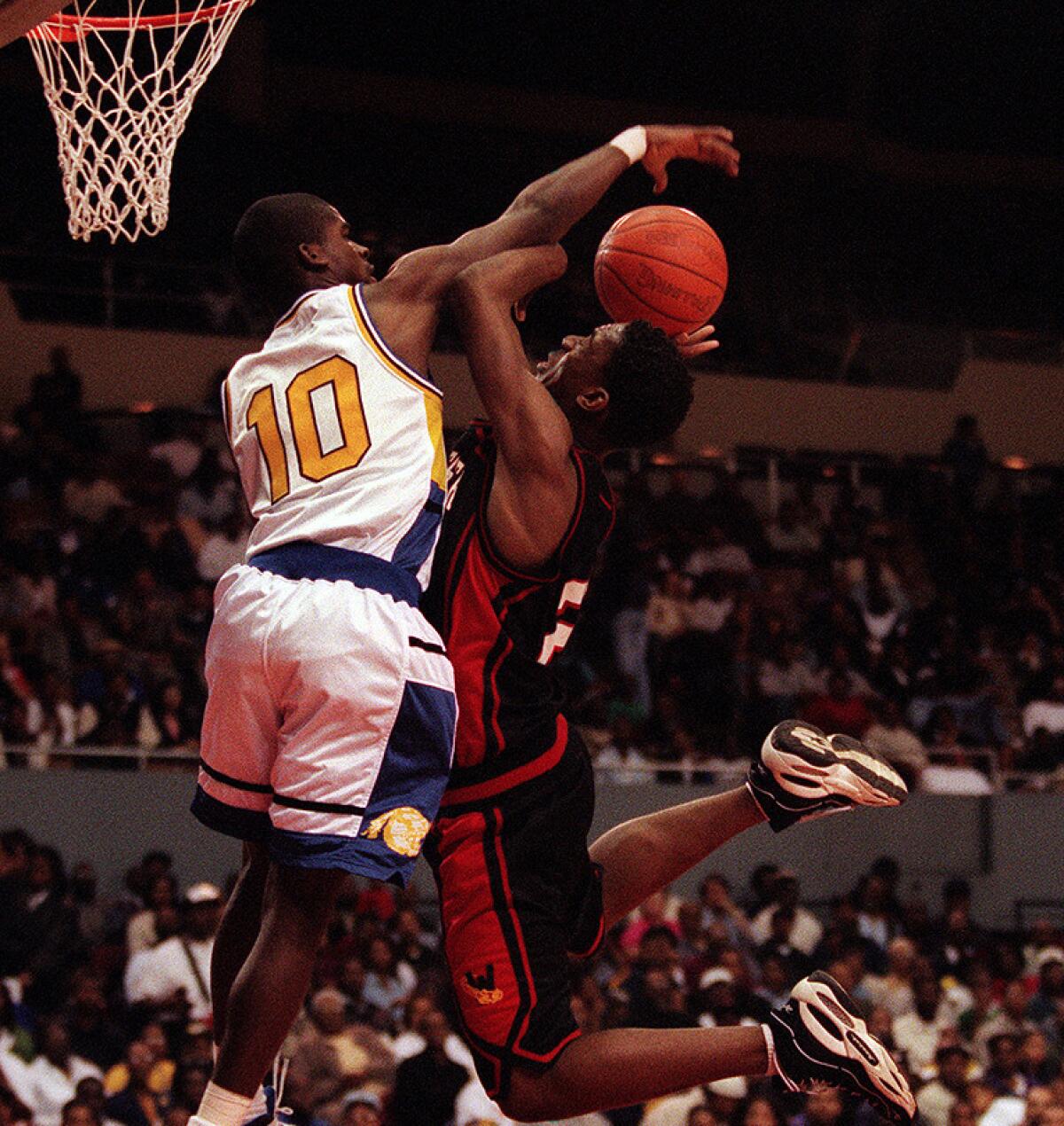 Crenshaw guard Kevin Bradley blocks a shot by Westchester's Albert Miller during the 1997 City Section championship basketball game at the L.A. Sports Arena.