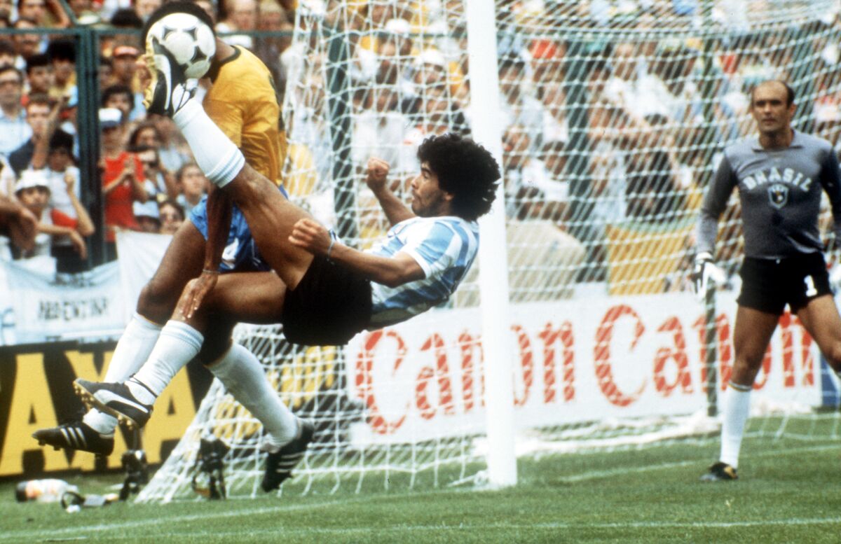 Diego Maradona delivers an overhead kick against Brazilian defender Luizinho in the 1982 FIFA World Cup
