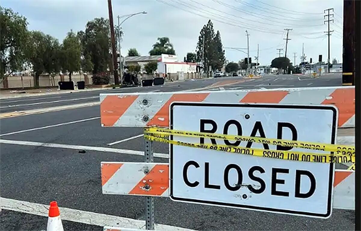 Road closed sign with police tape on it.