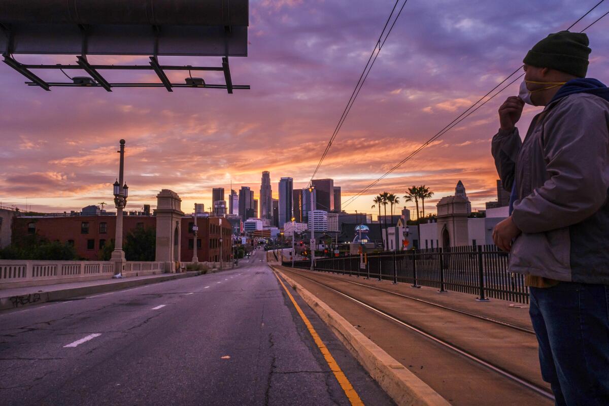 A pedestrian looks down an empty L.A. street at dusk
