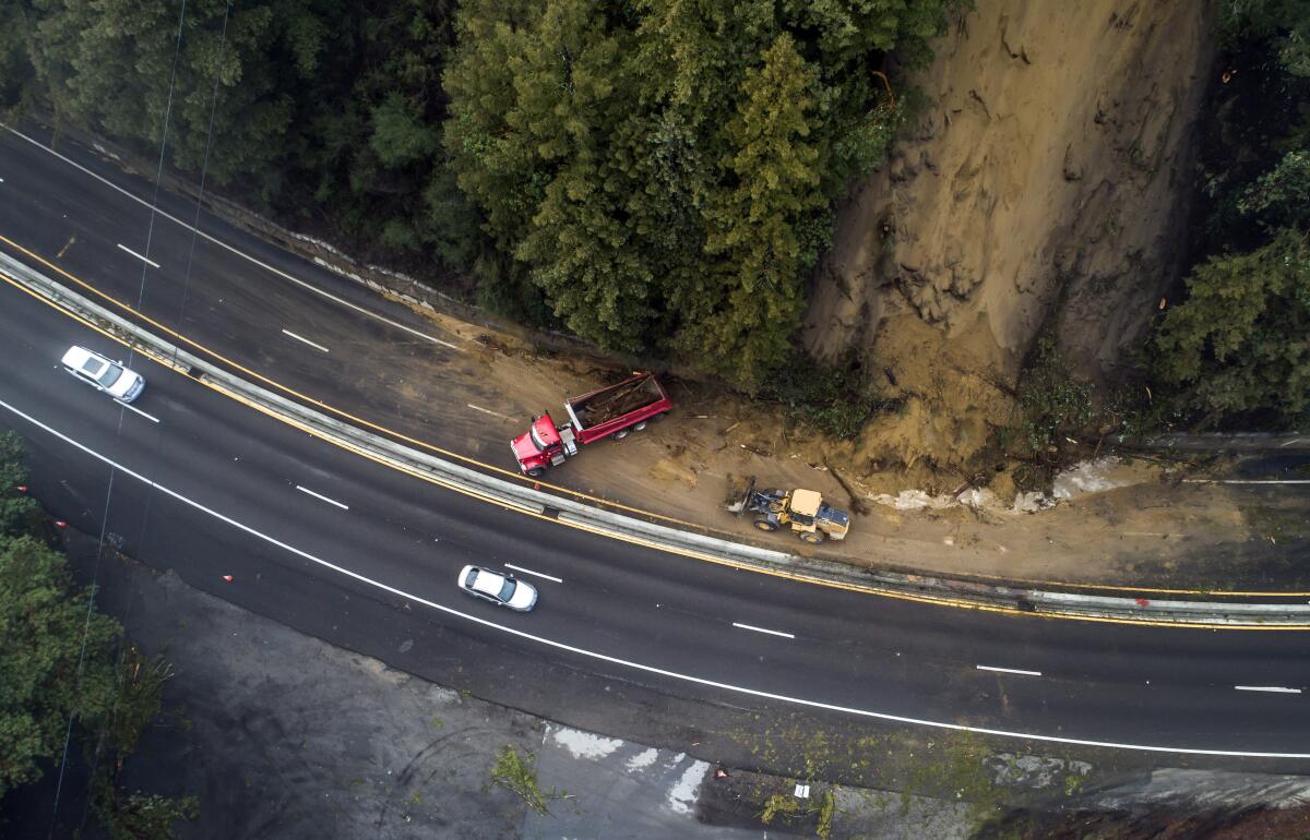Caltrans crews work to clear a mudslide on Highway 17 that resulted from heavy rain from an atmospheric river storm