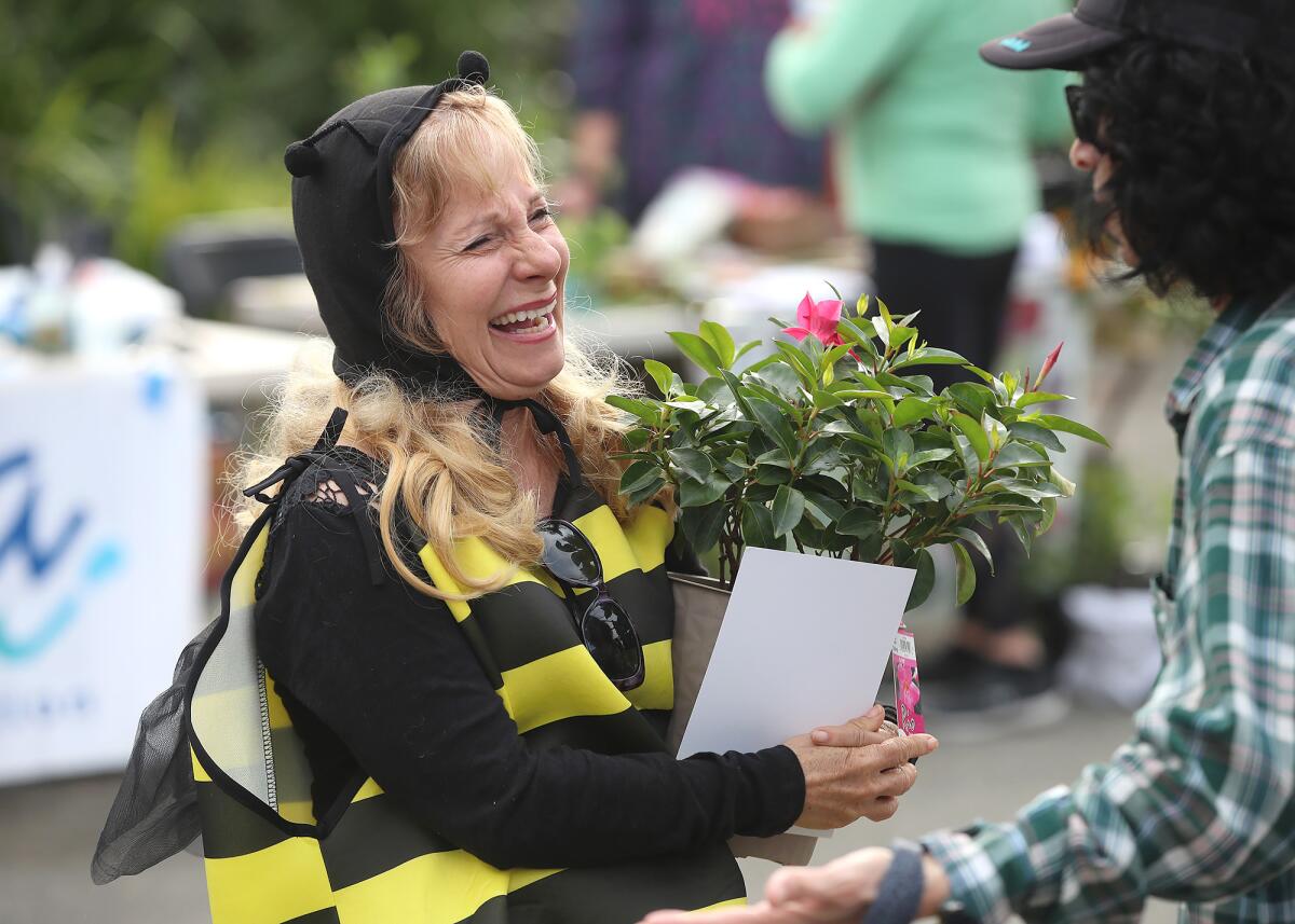 Dressed as a bee from the Laguna Beach Garden Club, Dee Perry greets Judie Mancuso, from left, on Thursday.