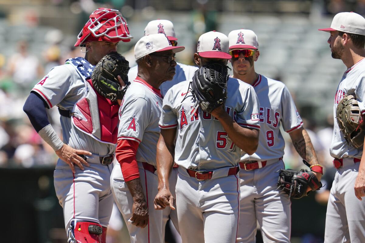 Pitcher Roansy Contreras, center, covers his face with his glove as players gather with coach Ron Washington on the mound