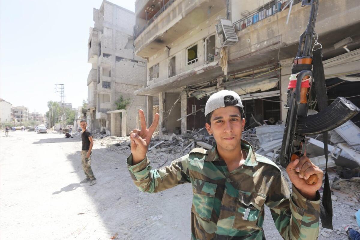 A Syrian soldier greets journalists in a town near Damascus on Friday.