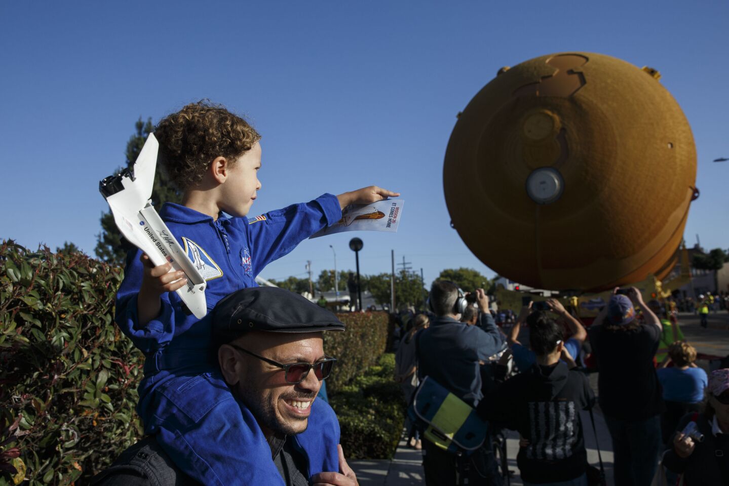 Darren Hackett carries son Sawyer, 4, dressed as an astronaut, as the ET-94 fuel tank makes its way to the California Science Center.