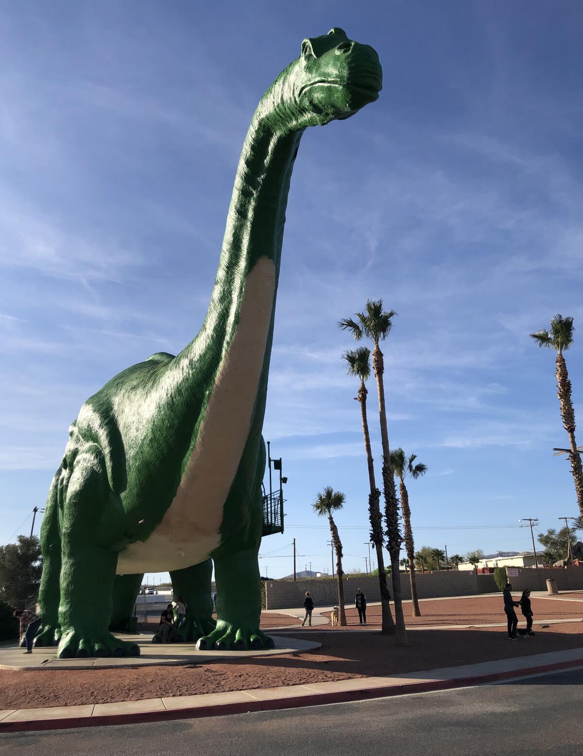 A large concrete apatosaurus next to a road.