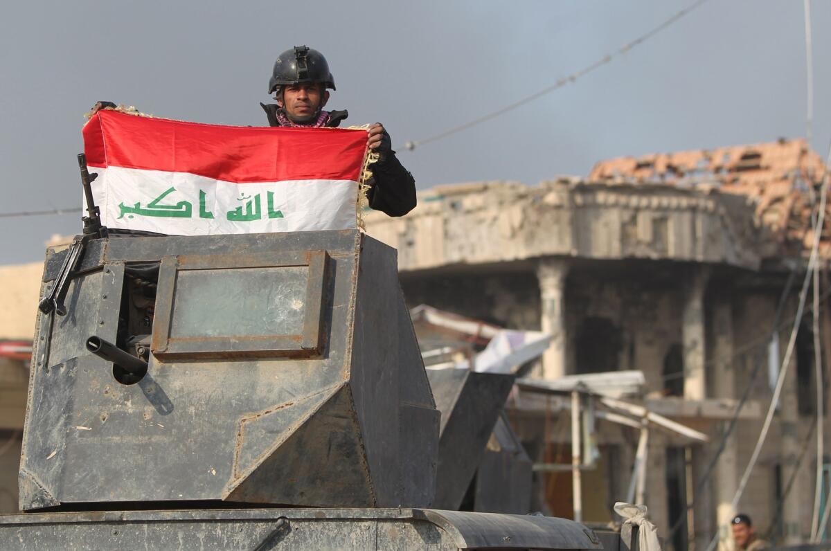 A member of Iraq's elite counter-terrorism service raises his national flag after Iraqi forces recaptured Ramadi