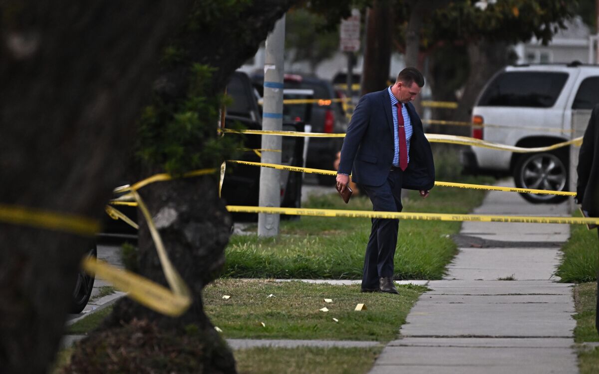 Law enforcement investigators comb the scene of a shooting along Blakely Avenue in Willowbrook.