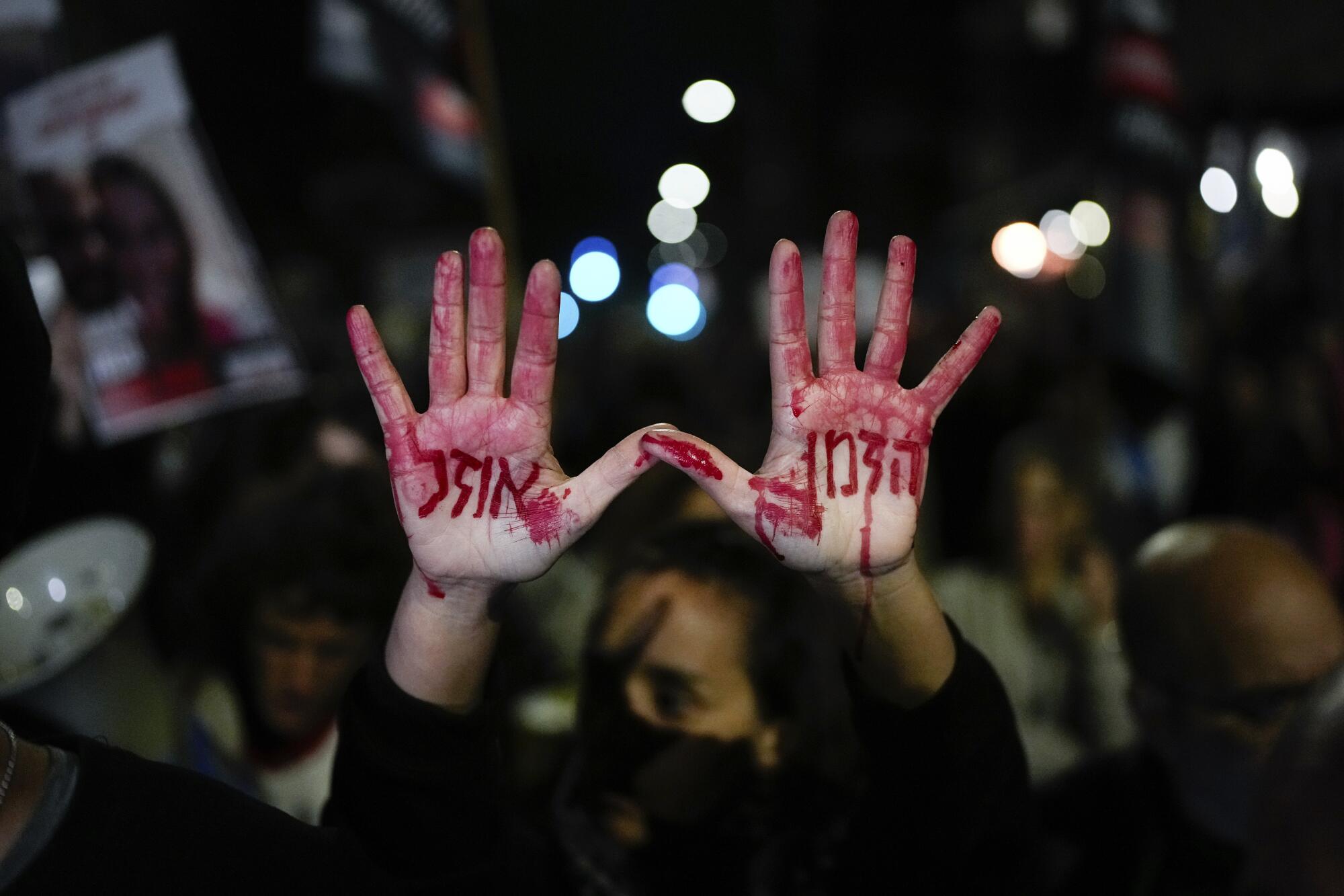 Israeli protester holds up hands with fake blood on them