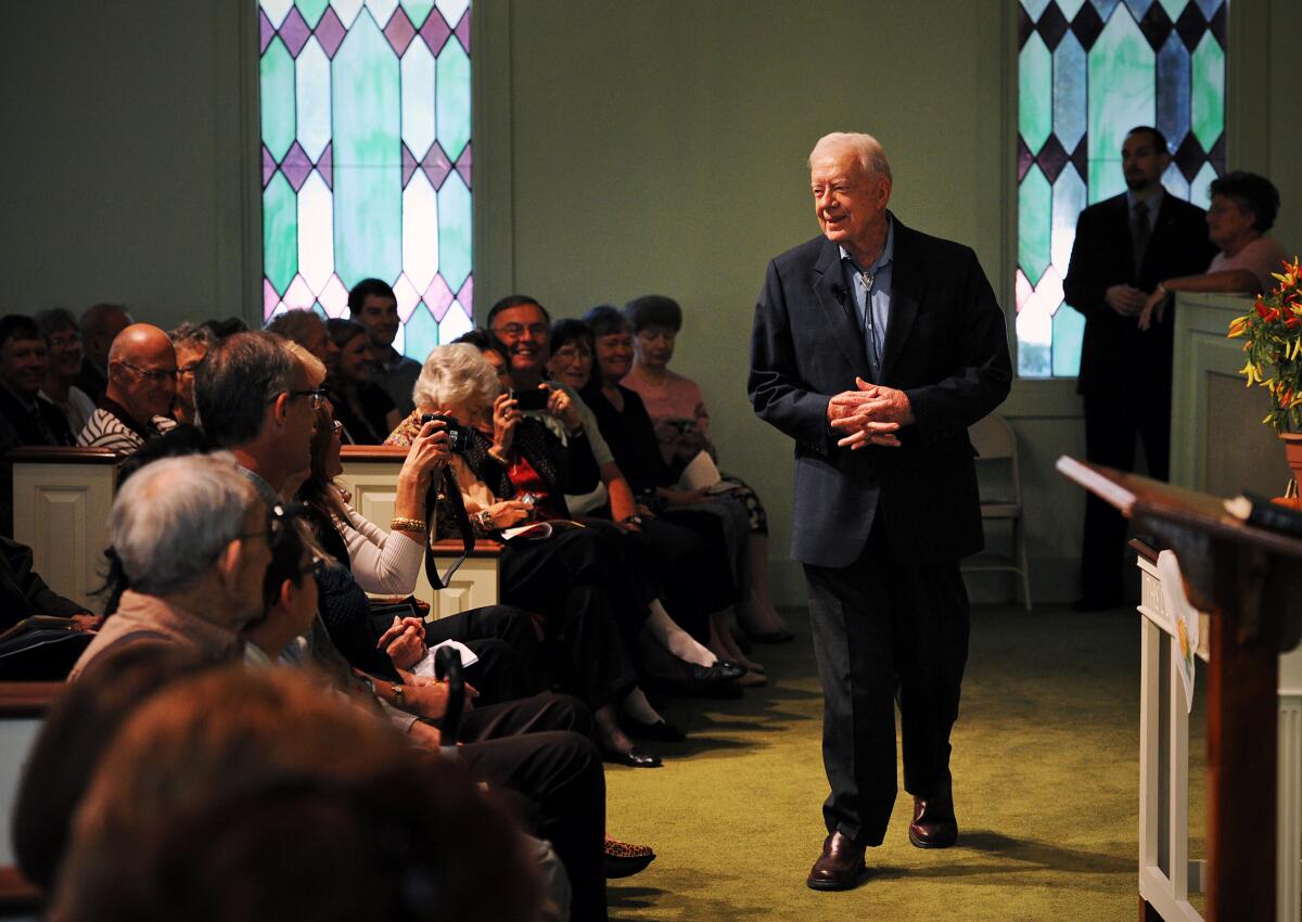 Jimmy Carter greets people in a church. 