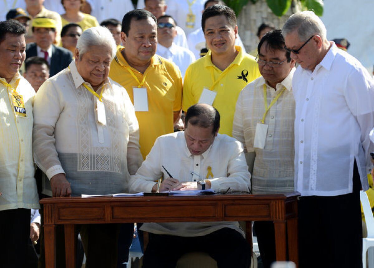 Philippines President Benigno Aquino III signs a bill Monday during ceremonies marking the 27th anniversary of its uprising against Ferdinand Marcos.