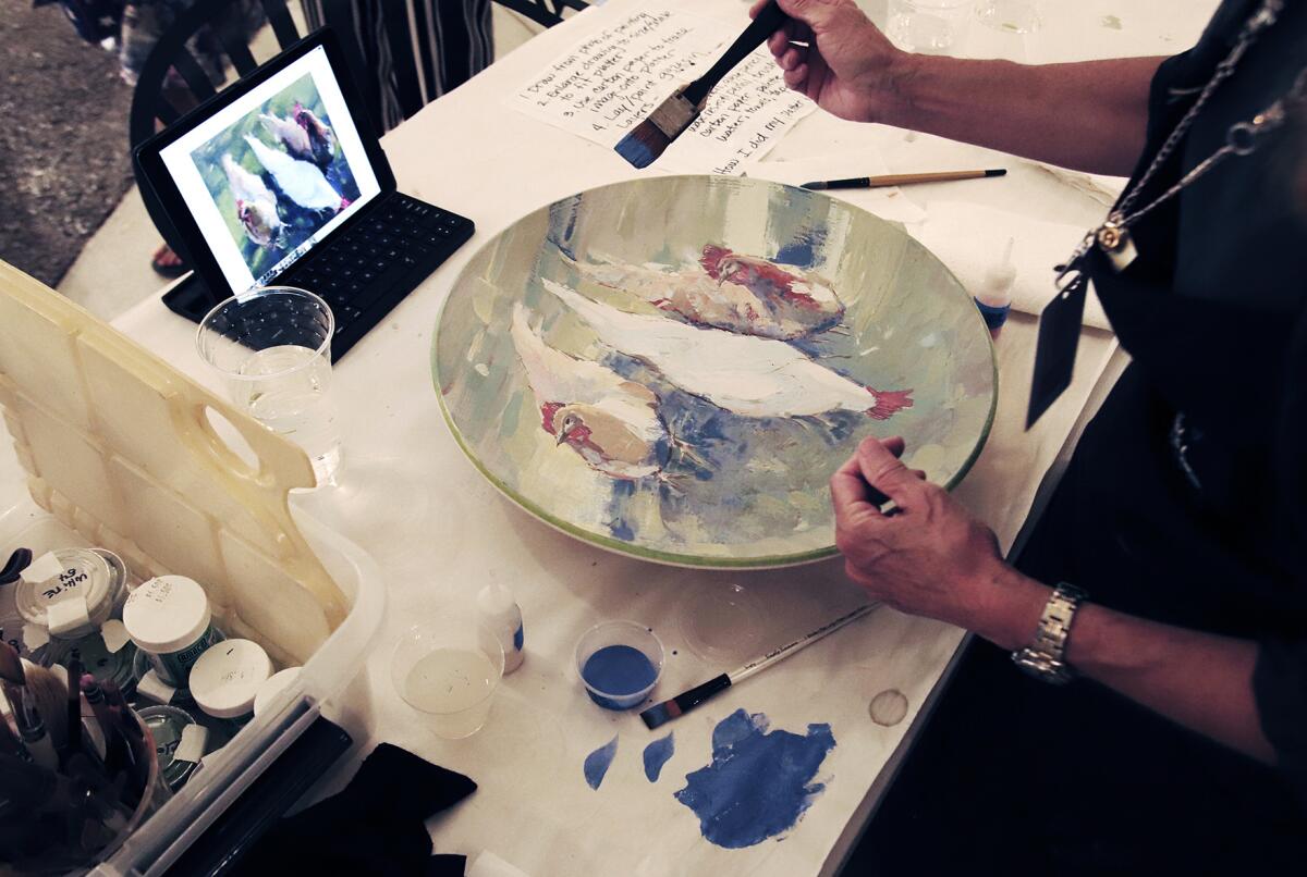 Susan Jarecky, from Orange, paints her platter "Three Hens" during the Platter Painting Party.