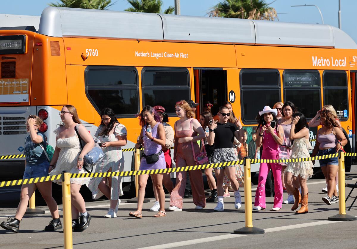 People walk next to an orange bus.