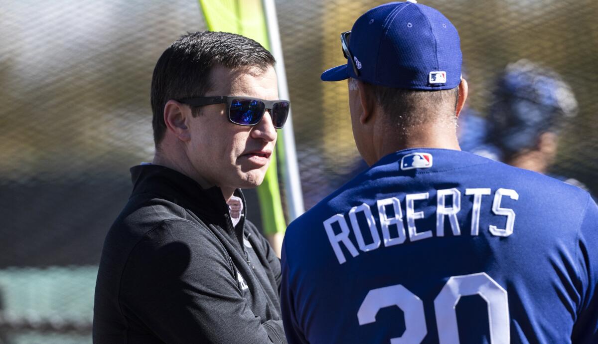 Dodgers executive Andrew Friedman chats with manager Dave Roberts during a spring training workout Feb. 19.