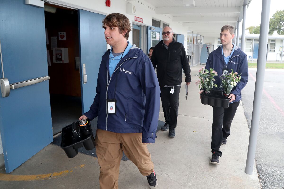 STEP students Quinn Peabody, left, and Parker Cope with John Hudson deliver flowers Wednesday at College Park Elementary.