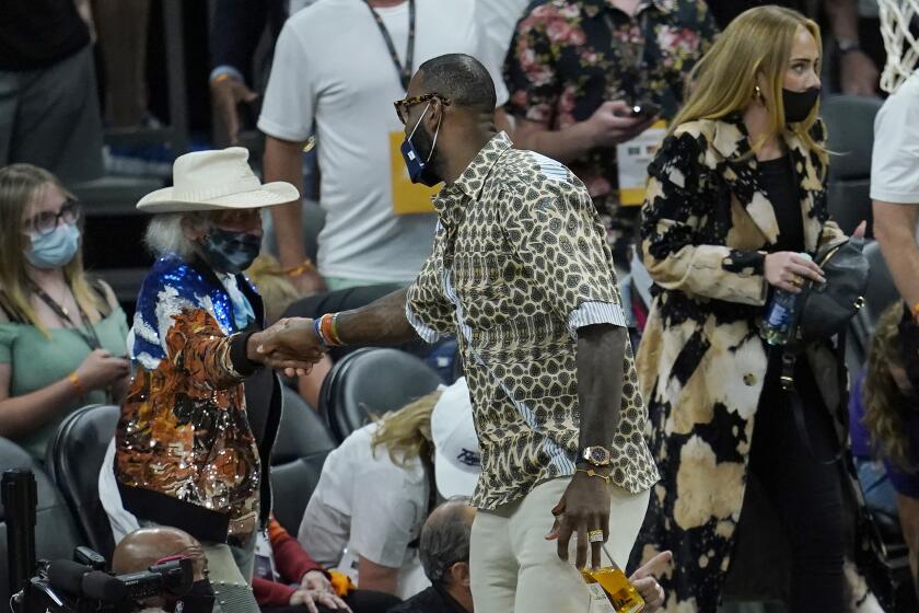 Los Angeles Lakers basketball player LeBron James, middle, greets fan James Goldstein during Game 5 of basketball's NBA Finals between the Phoenix Suns and the Milwaukee Bucks, Saturday, July 17, 2021, in Phoenix. Also pictured is musician Adele, right. (AP Photo/Ross D. Franklin)