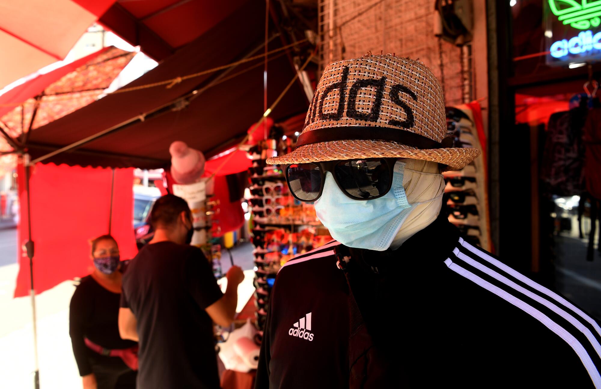 Customers shop along Maple Avenue in Los Angeles near a mannequin in a mask, hat, track jacket and sunglasses.
