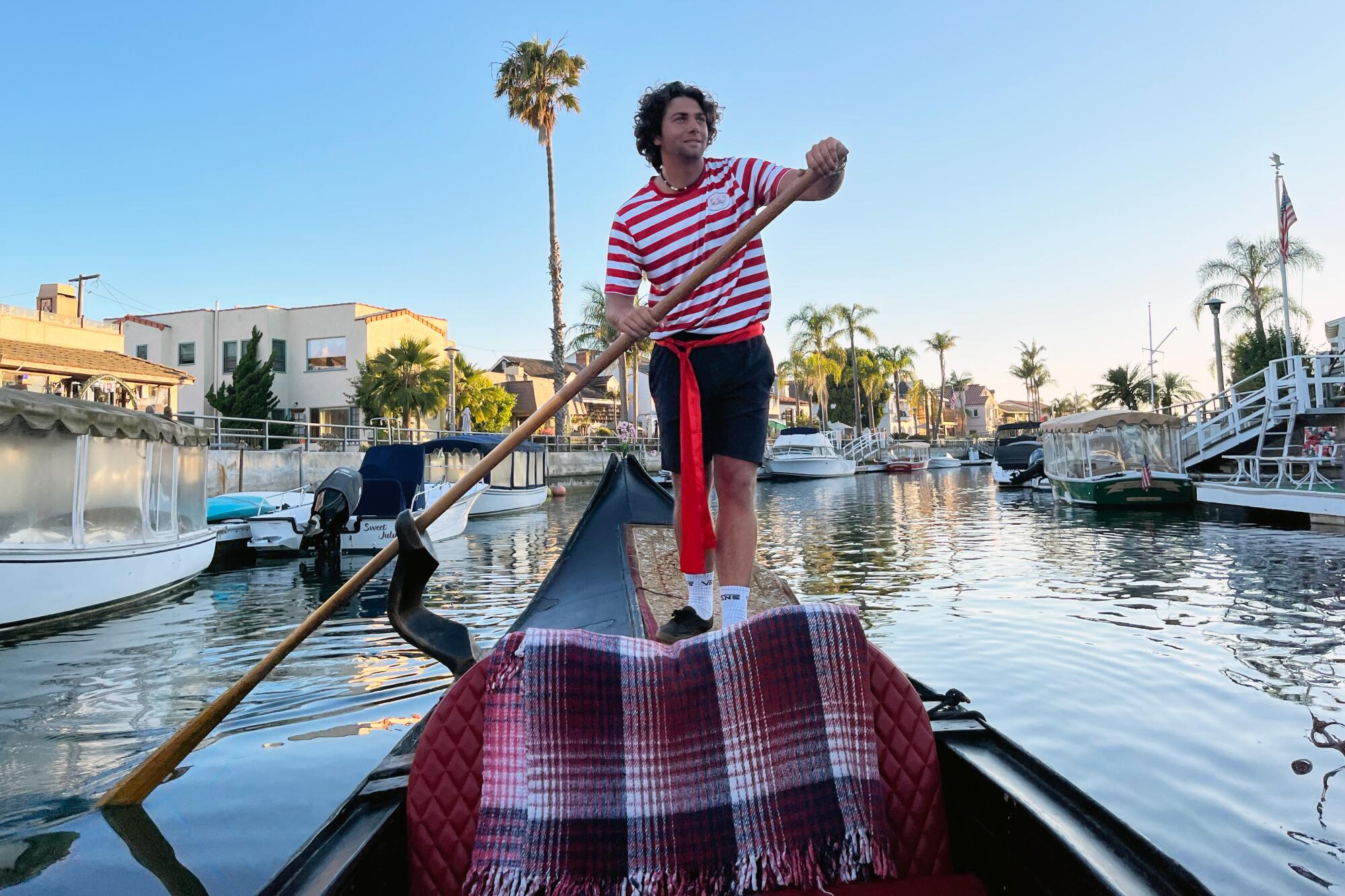 A gondolier standing at the back of a gondola.