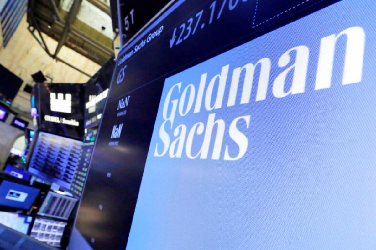 A computer with "Goldman Sachs" on it and a stock price indicator above it.