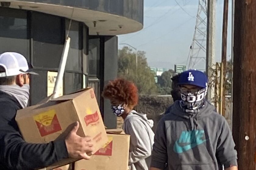 Angelou quarterback Omar Sahagun helps lift 25-pound food boxes to distribute to community members.