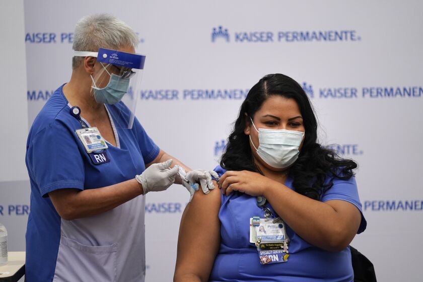 Nurse Helen Cordova, right, receives the Pfizer-BioNTech COVID-19 vaccine at Kaiser Permanente Los Angeles Medical Center in Los Angeles, Monday, Dec. 14, 2020. (AP Photo/Jae C. Hong)