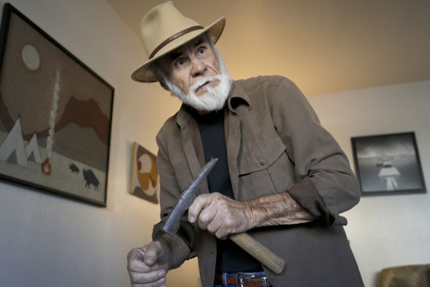 Field paleontologist Richard Cerutti, shown in his Imperial Beach apartment, holds a brick hammer that he uses to help loosen hardened sediment at some excavations