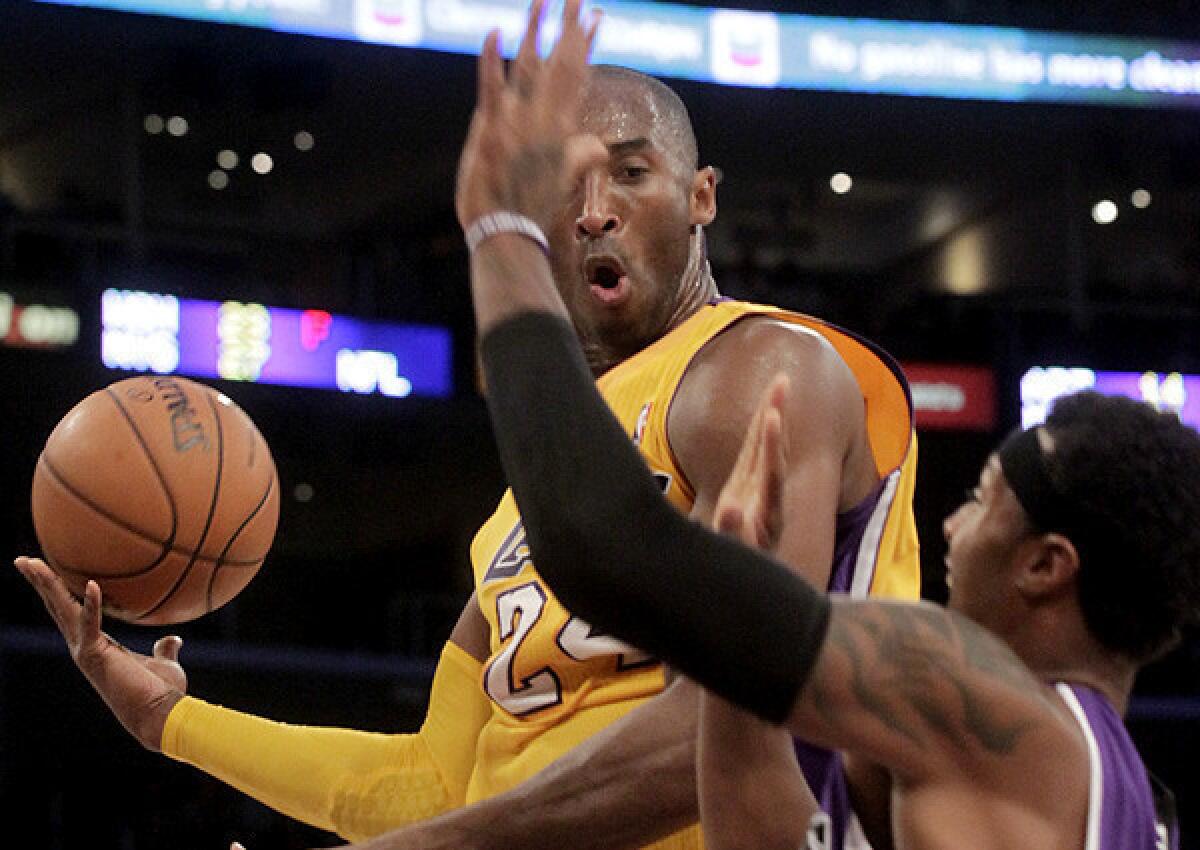 Lakers guard Kobe Bryant flips a no-look pass as his drive is cut off by Kings guard James Johnson in a preseason game Sunday.