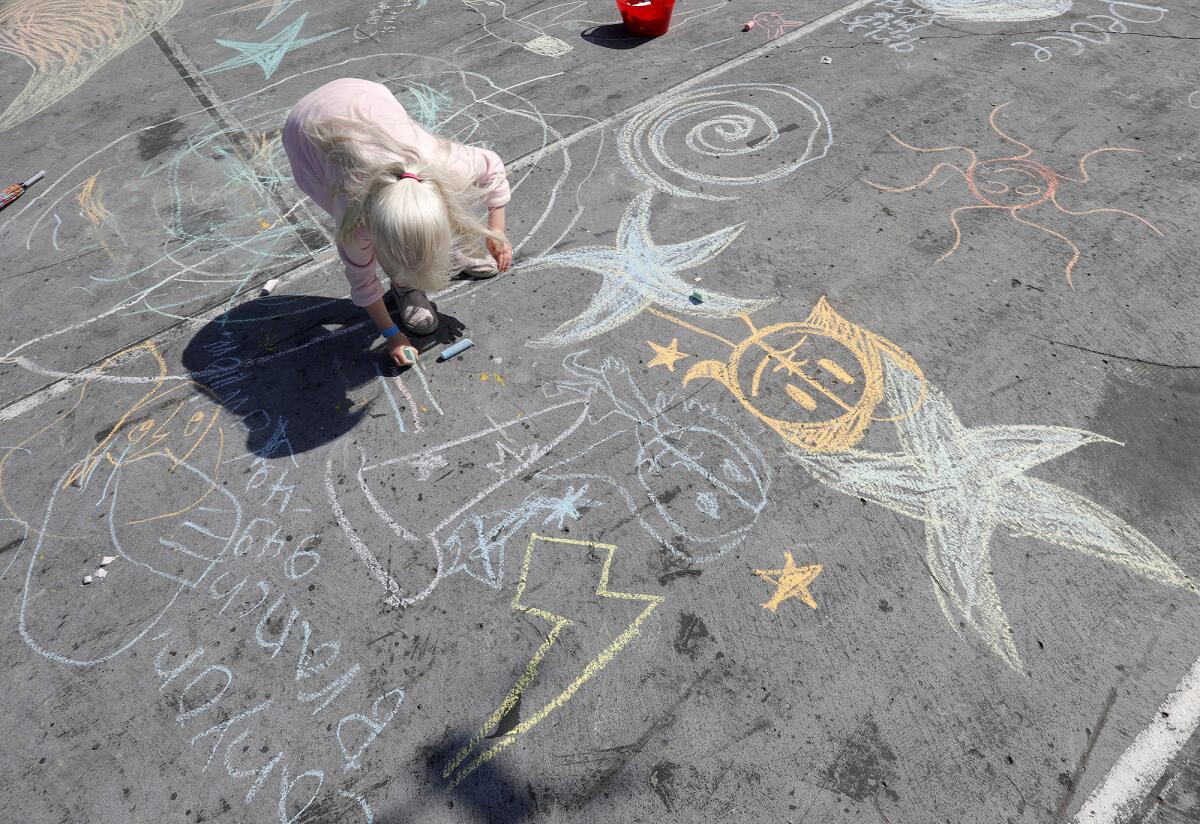 A youngster draws a line with chalk during the "Look Up" flash art experience run by artist Elizabeth Turk.