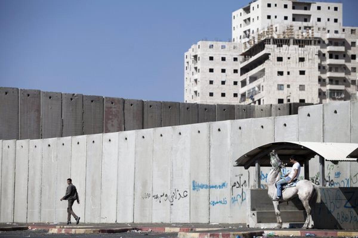 A Palestinian man walks next to the wall that separates the Shuafat refugee camp in East Jerusalem from the rest of the city. The Palestinian Authority would like East Jerusalem to become part of a new Palestinian state.