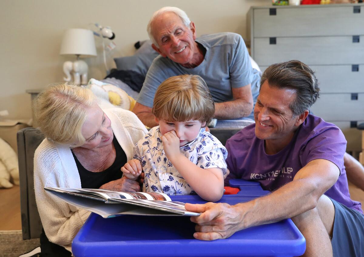 Dr. Justin West, right, his son Andrew, 7, center, who plays with his grandparents Jan and John West in his  home.