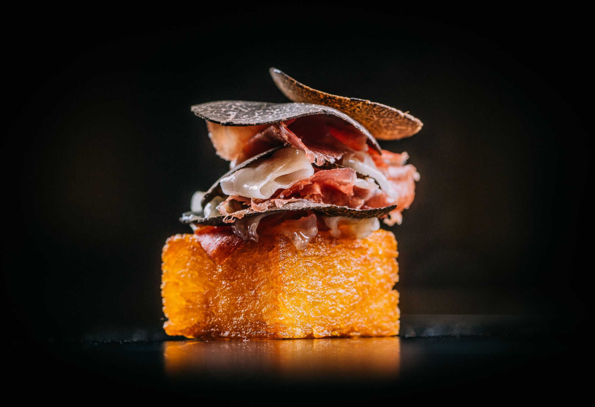 A finished shot by Eric Wolfinger shows a bite of crispy potato, Iberian ham and black truffle at Addison restaurant.
