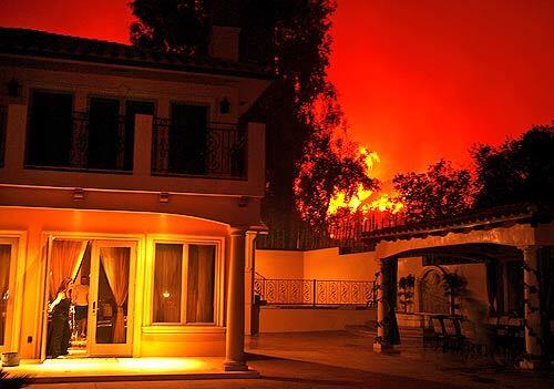 With flames approaching her home, Mary Afifi, 39, prepares to leave after police call for a mandatory evacuation. Firefighters moved in to protect structures from the brush fire in Griffith Park, where more than 200 acres were consumed in the blaze fanned by hot temperatures and dry winds.