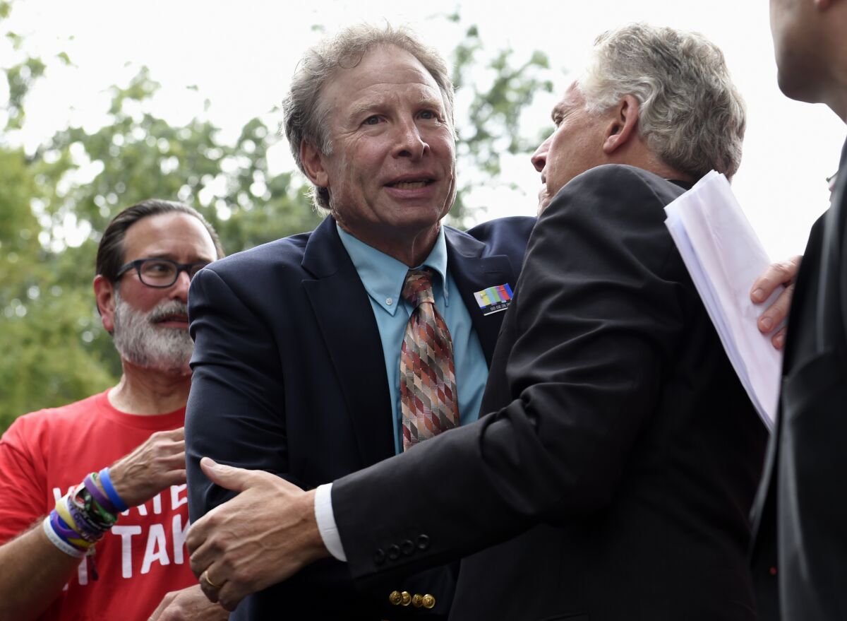 FILE - Andy Parker, father of WDBJ-TV reporter Alison Parker, who was shot dead on live television Aug 26, center, is hugged by Virginia Gov. Terry McAuliffe, right, after speaking at a rally against gun violence, Thursday, Sept. 10, 2015, on Capitol Hill in Washington. The father of a Virginia journalist fatally shot during a live broadcast in 2015 has conceded that he failed to make the ballot in the Democratic nomination contest for the 5th Congressional District. Andy Parker, who announced in January that he would seek to unseat incumbent GOP Rep. Bob Good, said in a statement Monday, April 19, 2022, that he would instead throw his support to Democratic nominee Josh Throneburg. (AP Photo/Susan Walsh, File)