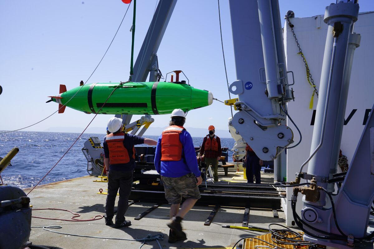 Scientists aboard the Research Vessel Sally Ride prepare to deploy a robot underwater.
