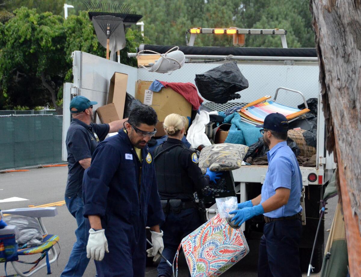 Workers loaded a truck with encampment belongings strewn along Avocado Avenue on Thursday.