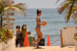 At Paradise Cove in Malibu, a bather carries boxed lunches on July 13.