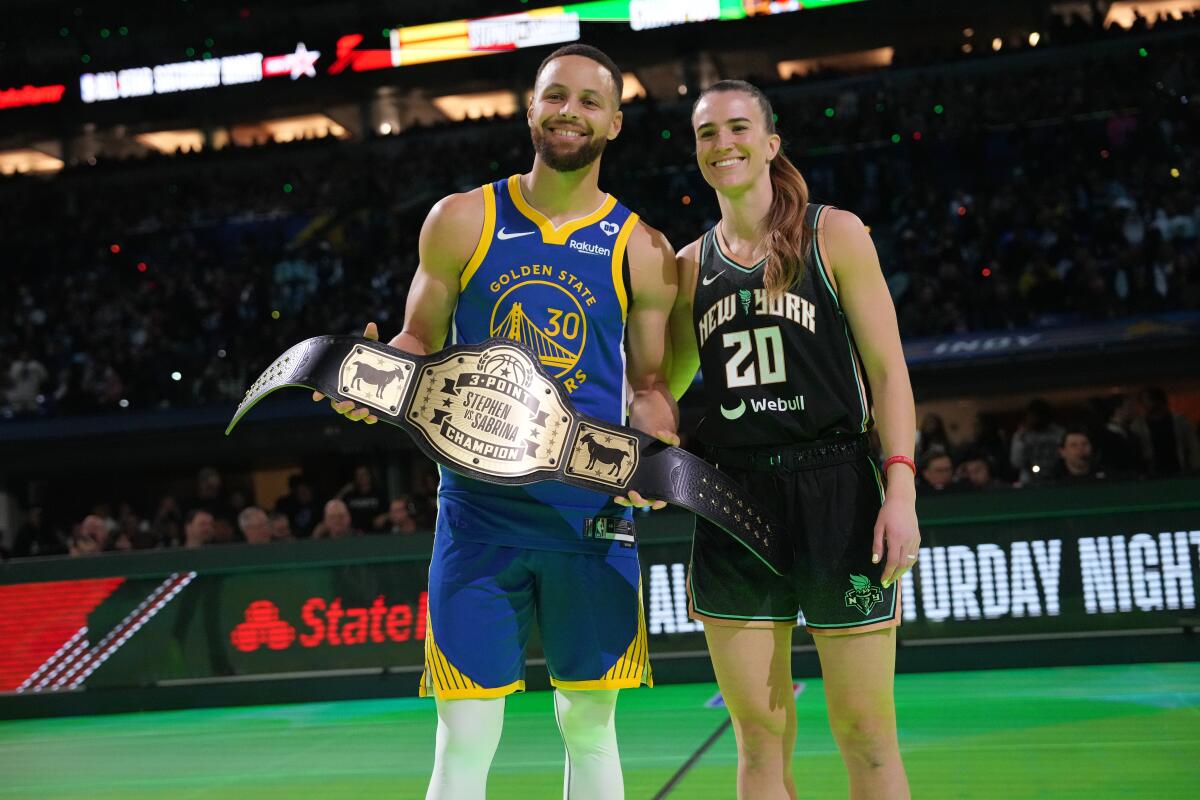 Golden State Warriors star Stephen Curry stands next to New York Liberty star Sabrina Ionescu.