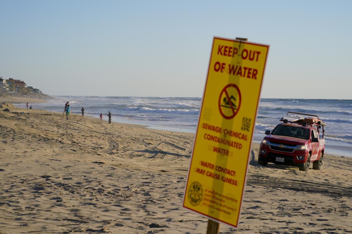 A beach closure sign warns of sewage pollution in Imperial Beach.