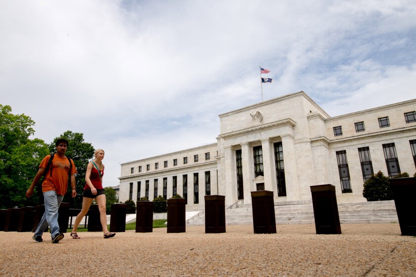 People walk past the Marriner S. Eccles Federal Reserve Board Building in Washington, D.C. on June 19.