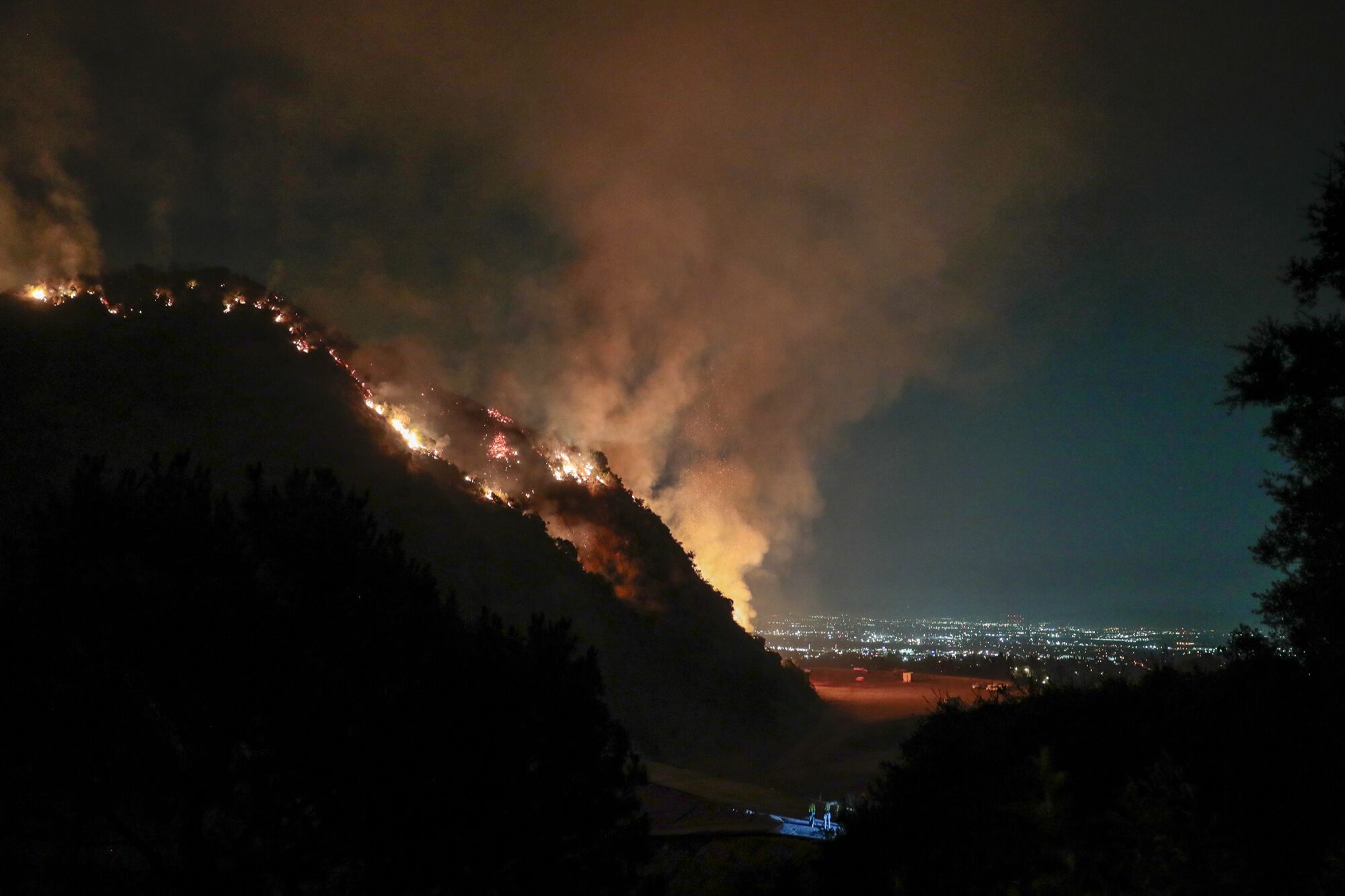 Firefighters look on from Sawpit Canyon as the Bobcat fire burns in the Angeles National Forest.
