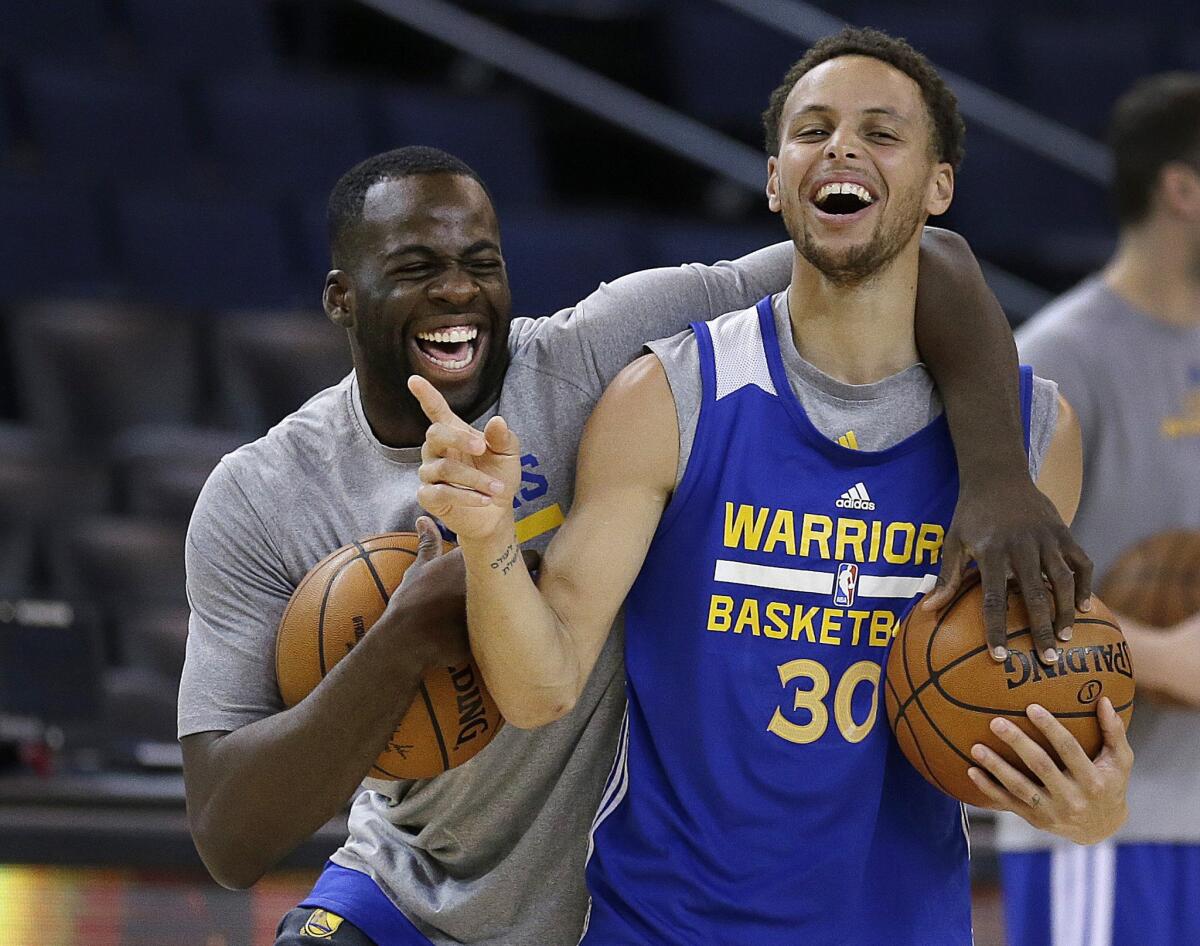 Warriors forward Draymond Green and guard Stephen Curry (30) share a laugh during practice Wednesday in Oakland.