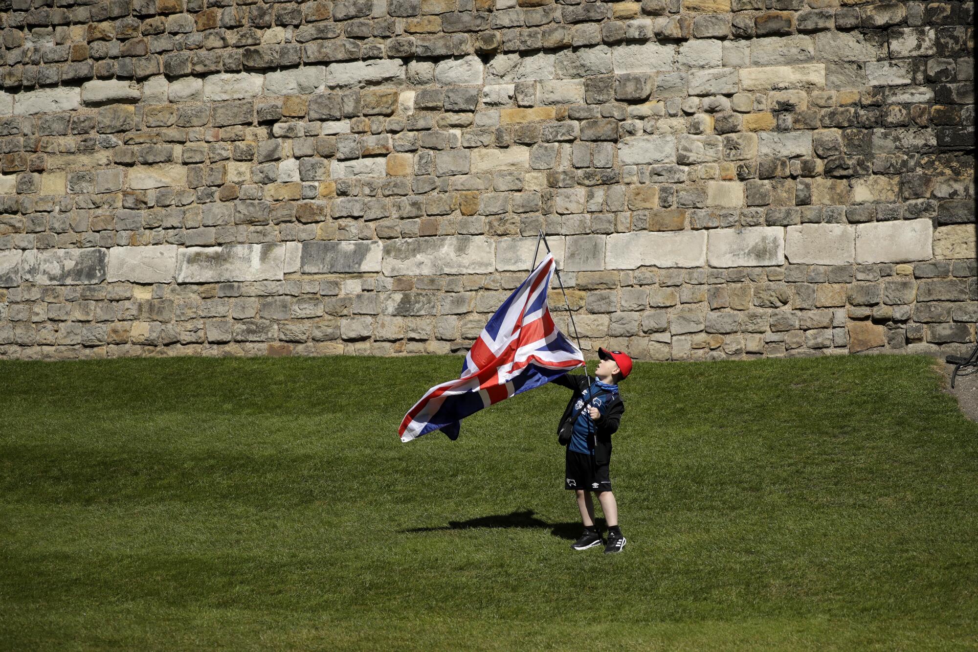 Jayden, 8, holds a Union Jack outside Windsor Castle on the grass.