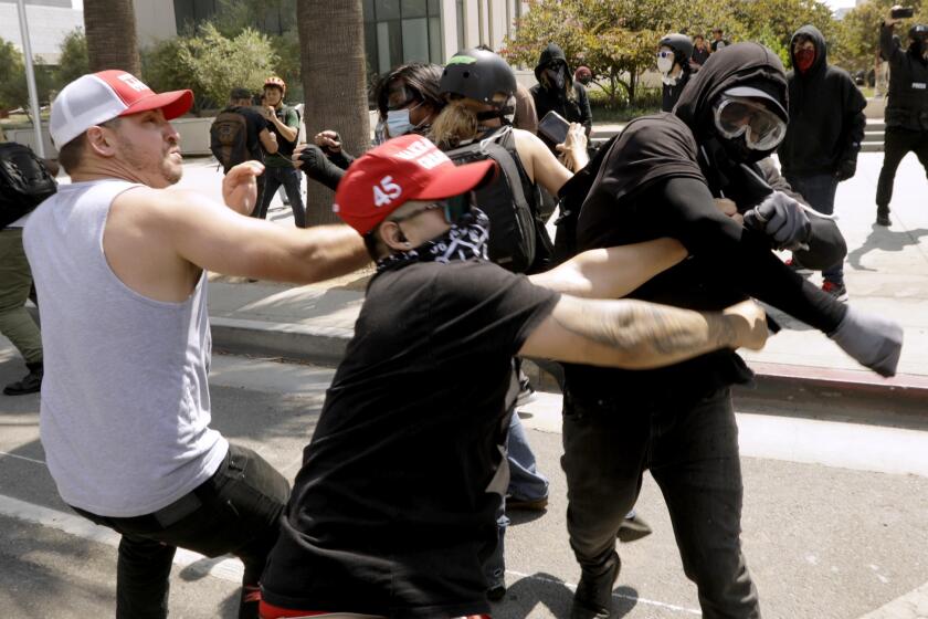 LOS ANGELES, CA - AUGUST 14, 2021 - - Advocates against vaccine mandates, left, confront pro-vaccine advocates in front of the L.A.P.D. Headquarters in downtown Los Angeles on August 14, 2021. One man was stabbed during the melee and was taken by paramedics to a nearby hospital. (Genaro Molina / Los Angeles Times)