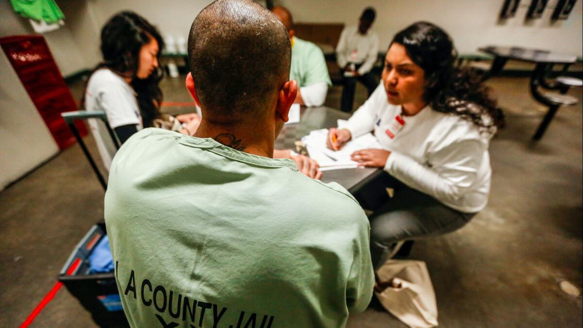 Volunteer Elizabeth Garcias-Bynum, right, assists an inmate. So far 388 people from Men's Central Jail and women's facility in Lynwood have registered.