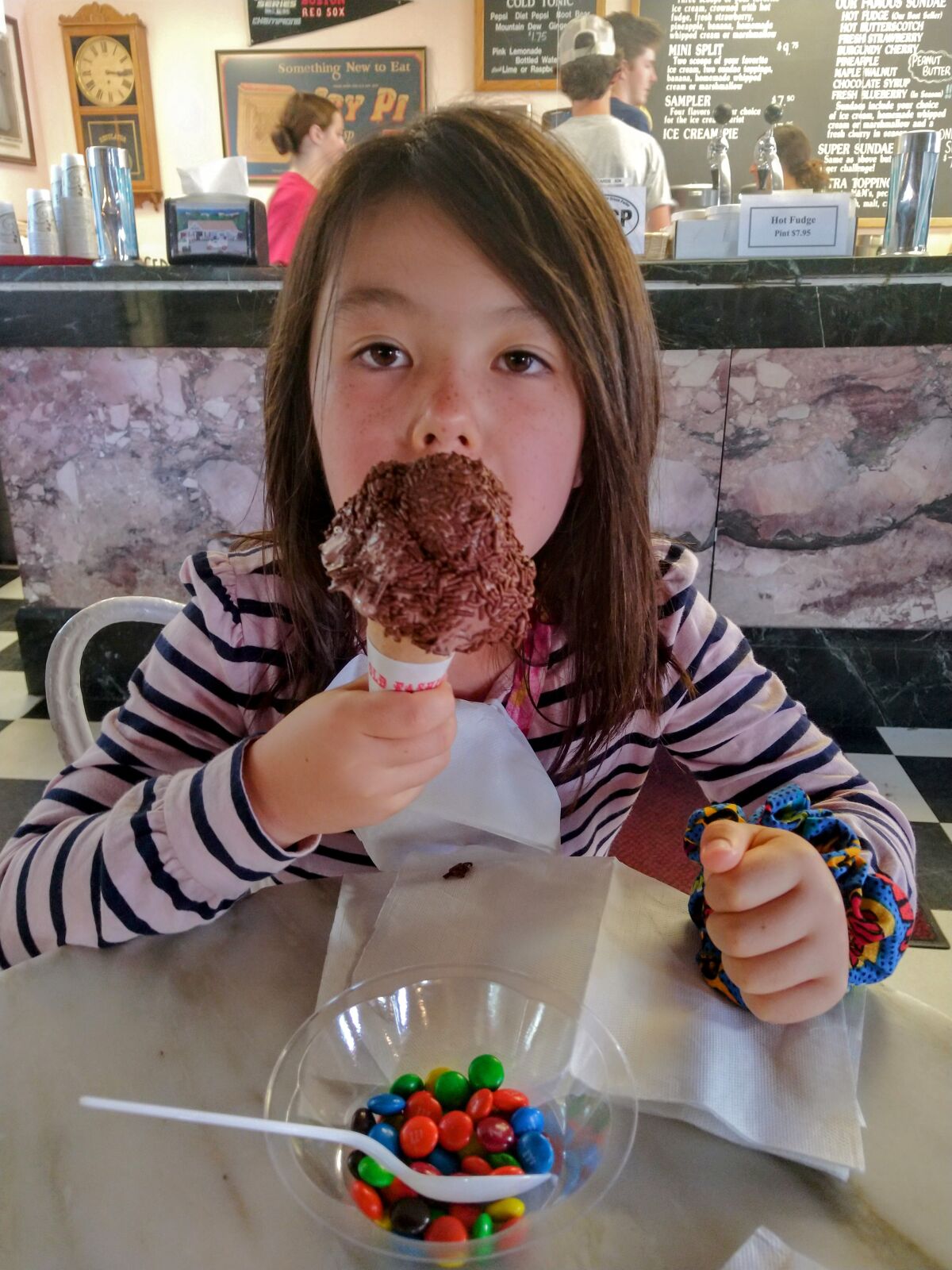 A child takes a bite of chocolate ice cream
