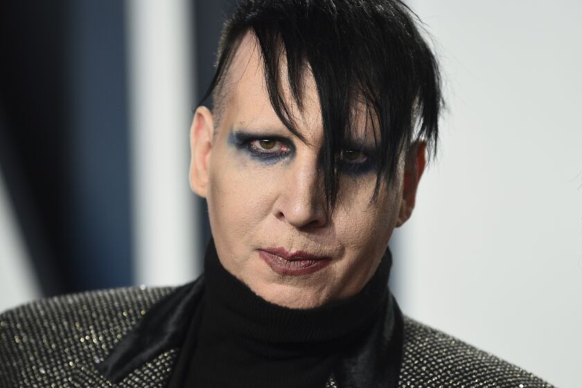 A man with dark hair wearing eye makeup and lipstick