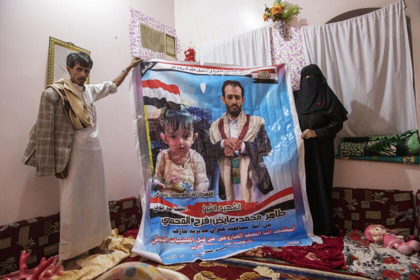 Gamila Salih Ali, right, and Ahmed Farag, mother and uncle of two-year-old Liyan Taher, seen in poster at left, who was killed with her father 32-year-old Taher Farag, seen in poster at right, in a ballistic missile and an explosive-laden drone fired by Yemen's Houthi rebels that hit a fuel station on June 5, 2021 in Rawdha neighborhood, show a poster with photos of them at their home in Marib, Yemen, Saturday, June 19, 2021. (AP Photo/Nariman El-Mofty)