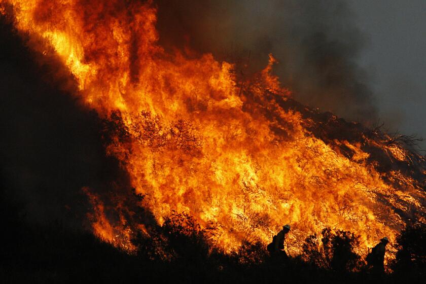 Firefighters are silhouetted against a blazing hillside in Sunland on Tuesday, Sept. 1, 2009.